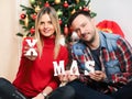 Happy couple celebrating christmas and new year eve at home holding wooden letters Royalty Free Stock Photo