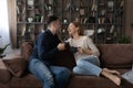 Happy couple chatting, holding cups of tea, relaxing on couch Royalty Free Stock Photo