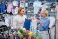 Happy couple choose infant clothes in the shopping center. Royalty Free Stock Photo