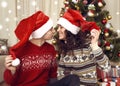 Happy couple kiss in christmas decoration at home. New year eve, ornated fir tree. Winter holiday and love concept. Royalty Free Stock Photo