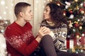 Happy couple kiss in christmas decoration at home. New year eve, ornated fir tree. Winter holiday and love concept. Royalty Free Stock Photo