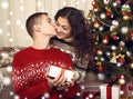 Happy couple kiss in christmas decoration at home. New year eve, ornated fir tree. Winter holiday and love concept. Royalty Free Stock Photo
