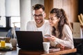 Happy couple communicating while using credit card and laptop for online shopping at home Royalty Free Stock Photo