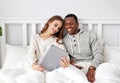 Happy couple with computer tablet and smartphone on winter morning in bed Royalty Free Stock Photo