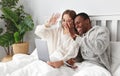 Happy couple with computer tablet and smartphone on winter morning in bed Royalty Free Stock Photo