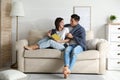 Happy couple covered with warm dark blue plaid reading book on sofa at home