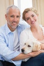 Happy couple cuddling with puppy on sofa Royalty Free Stock Photo