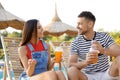 Couple with cups of refreshing drink resting in deck chairs