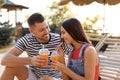 Happy couple with cups of refreshing drink resting in deck chairs outdoors