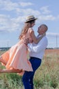 Happy couple dancing in the field. brunette in cream dress and bald man in white shirt and blue pants. love story. husband and