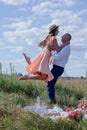 Happy couple dancing in the field. brunette in cream dress and bald man in white shirt and blue pants. love story. husband and