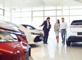 Couple and the dealer selling cars look the car in the showroom. Royalty Free Stock Photo