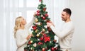 Happy couple decorating christmas tree at home Royalty Free Stock Photo