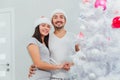 Happy Couple Decorating Christmas Tree in their Home. Smiling Man and Woman together Celebrating Christmas or New Year Royalty Free Stock Photo