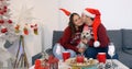 Happy couple with dog sitting on the sofa near Christmas tree Royalty Free Stock Photo