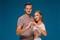 Happy couple dressed casual clothes, making heart shape from fingers, studio portrait on blue background Royalty Free Stock Photo