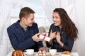 Happy couple drinking coffee and having fun, man give very funny gifts - love and holiday concept Royalty Free Stock Photo