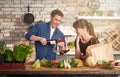 Happy couple drinking wine at home while cooking in the kitchen Royalty Free Stock Photo