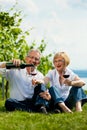 Happy couple drinking wine at lake in summer