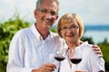 Happy couple drinking wine at lake in summer