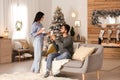 Happy couple with drinks in room decorated for Christmas