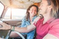 Happy couple driving vintage minivan for a summer road trip - Trendy people having fun on holiday vacation traveling around the Royalty Free Stock Photo