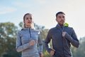 Happy couple with earphones running outdoors Royalty Free Stock Photo