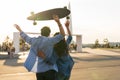 Happy couple enjoy sunset embrace with arms raised hold longboard. Happiness and freedom concept Royalty Free Stock Photo