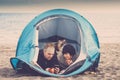 Happy couple enjoy technology and freedom with a tent placed at the beach near the sea water - alternative wild and free vacation Royalty Free Stock Photo