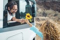 Happy couple enjoy travel with camper van. Man give a flower to her girlfriend outside the vehicle. Road trip destination and off Royalty Free Stock Photo