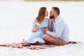 Happy couple enjoying picnic on the white sand beach and drinking wine or champagne during romantic dinner, young couple kissing a Royalty Free Stock Photo