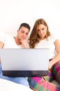 Happy couple enjoying using laptop computer in bed Royalty Free Stock Photo