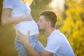 Happy couple expecting baby, happy man kissing belly of pregnant woman, young family and new life concept Royalty Free Stock Photo