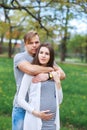 Happy couple expecting pregnancy portrait in park