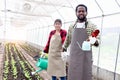 Happy couple farmer family work together in vegetable garden at countryside, Asian woman gardener and African man hold watering Royalty Free Stock Photo