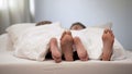 Happy couple feet in honeymoon bed, lovely conversation in morning, marriage Royalty Free Stock Photo