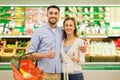 Happy couple with food basket at grocery store Royalty Free Stock Photo