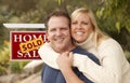 Happy Couple in Front of Sold Real Estate Sign Royalty Free Stock Photo