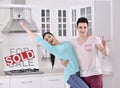 Happy Couple in Front of Sold Real Estate Sign Royalty Free Stock Photo