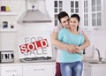 Happy Couple in Front of Sold Real Estate Sign Royalty Free Stock Photo