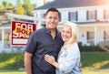 Happy Couple In Front of Sold Real Estate Sign and Beautiful House Royalty Free Stock Photo