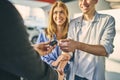 Happy couple getting a car key from stylish sale manager Royalty Free Stock Photo