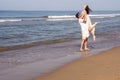 Happy couple at the golden sandy beach. Man holding woman in his arms with love. Royalty Free Stock Photo