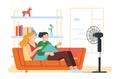 Happy couple guy and girl chill under electric fan at home in summer heat. Man and woman sitting on sofa. Air Royalty Free Stock Photo