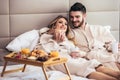 Happy couple having breakfast in luxury hotel room, watching TV Royalty Free Stock Photo