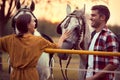 Happy couple having fun on the horse ranch. Fun on countryside, sunset golden hour. Freedom nature concept