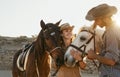 Happy couple having fun with horses inside stable - Young farmers sharing time with animals in corral ranch Royalty Free Stock Photo