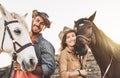 Happy couple having fun with horses inside stable - Young farmers sharing time with animals in corral ranch Royalty Free Stock Photo