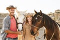 Happy couple having fun with horses inside stable - Young farmers sharing time with animals in corral ranch Royalty Free Stock Photo