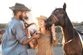 Happy couple having fun with horses inside stable - Young farmers sharing time with animals in corral ranch Royalty Free Stock Photo